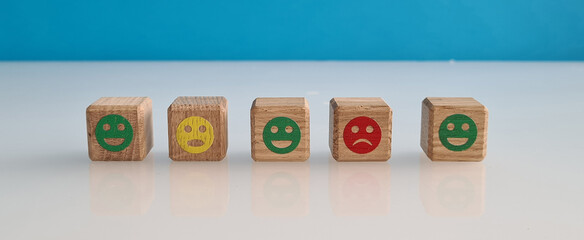 Happy sad and neutral smiles on wooden blocks on blue background