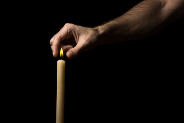 Man's hand extinguishes a burning candle on a black background