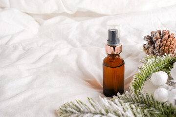Cosmetic product oil or face serum on white bed background with decorations. Winter skin care