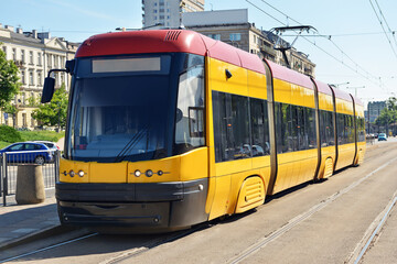 Naklejka na ściany i meble Modern yellow tram on railways in city