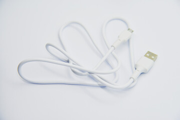White USB cable for charging the phone on a white background. White cord for charging gadgets.