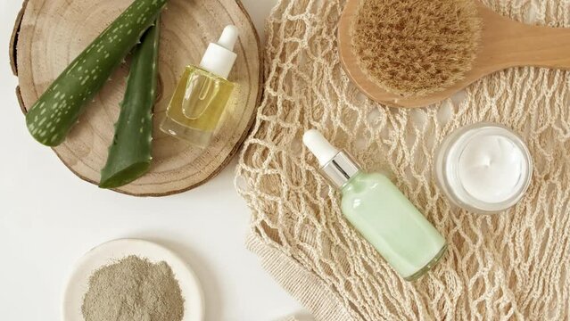 Eco friendly products on white background with green Aloe vera. Gel, fluid, collagen serum, essential oil, salt, massage brush. Natural organic skin care eco-cosmetics. flat lay. High quality 4k