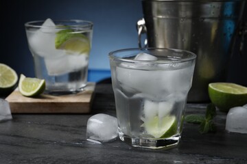 Glasses of vodka, lime, mint and ice on black marble table