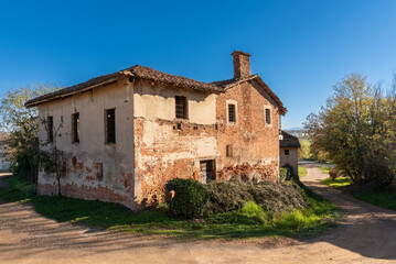 Fototapeta na wymiar Ancient abandoned farmhouse typical of the countryside near a country road in the province of Cuneo, Piedmont, Italy