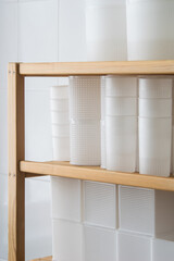 White plastic cheese forms, molding glasses on wooden shelves. Private small-scale cheese factory