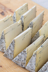 Fototapeta na wymiar Blue cheese pieces on a wooden board, selective focus. Dorblu danishn blue roquefort stilton craft cheese.