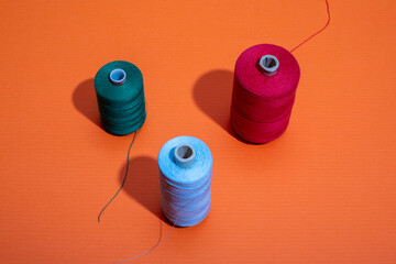 Three coils with colored threads on a colored background