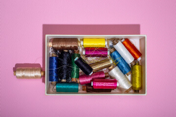 A box with multi colored coins of different threads on a colored background
