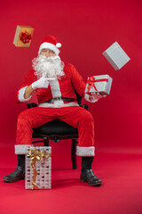 Portrait von einem verkleideten Weihnachtsmann mit Geschenk, isoliert auf roten Hintergrund im Studio mit Platzhalter