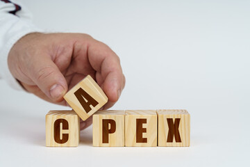 On a white surface, a man stacks cubes with the inscription - Capex