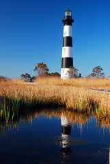 The Bodie Island Lighthouse in the North Carolina Outer Banks, is reflected in the water of the...