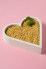 Concept of cooking, uncooked ptitim, on pink background