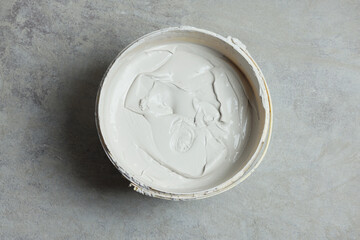 Bucket with plaster on concrete floor, top view