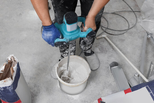 Professional worker mixing plaster in bucket indoors, closeup