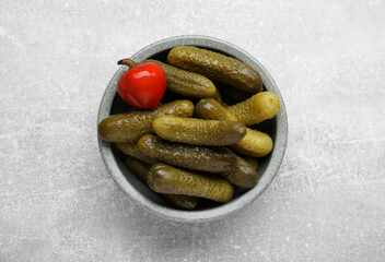 Bowl of pickled cucumbers and pepper on light grey table, top view