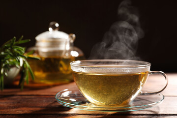 Cup of aromatic herbal tea on wooden table. Space for text