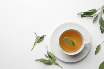 Cup of aromatic herbal tea with sage on white table, flat lay. Space for text