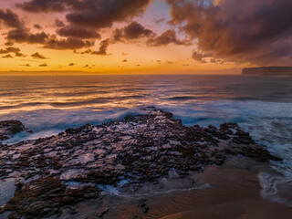 Obraz premium Surfs up sunrise at the seaside with scattered clouds
