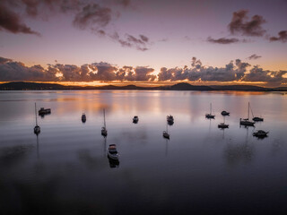Naklejka premium Aerial sunrise waterscape with boats, clouds and reflections
