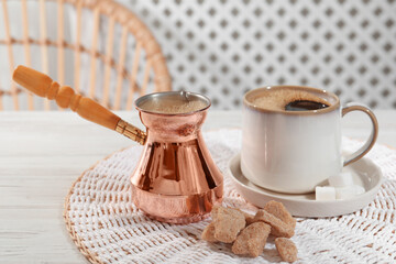 Turkish coffee. Cezve and cup with hot aromatic coffee and sugar on white wooden table