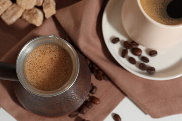 Turkish coffee. Cezve and cup with hot aromatic coffee, beans and sugar on table, flat lay