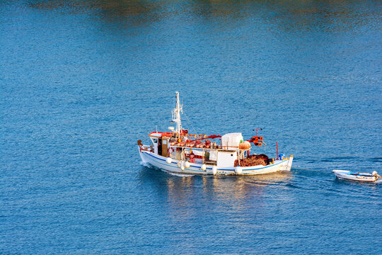A traditional wooden fishing boat floating on the colorful waters, Ermioni, Greece
