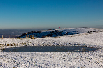 Fototapeta na wymiar Snow on Ditchling Beacon in Sussex, with a Frozen Dew Pond in the Foreground