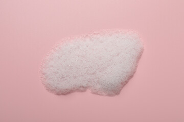Drop of fluffy soap foam on pink background, top view