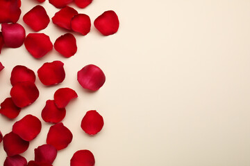 Red rose petals on beige background, top view. Space for text