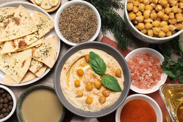 Delicious creamy hummus with chickpeas and different ingredients on wooden table, flat lay