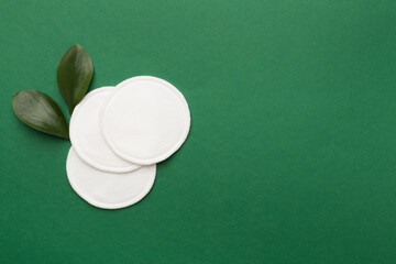 Cotton reusable pads with leaves on color background. Top view. © Liami