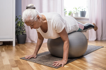 Middle aged woman in plank position keeps fit in her home