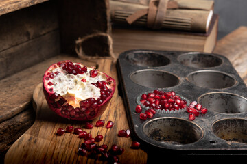 Pomegranate fruit arias on a wooden cutting board on a table. - obrazy, fototapety, plakaty