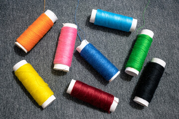 Fototapeta na wymiar Spools of colorful threads on gray cotton surface