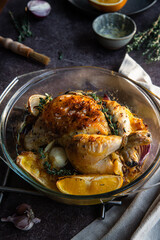 Oven roasted coquelet jaune (yellow spring chicken) with oranges, onions and herb butter in glass baking dish.