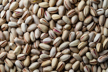 Pistachios texture and background. Pile pistachio kernels nuts with shell, closeup. Pistachio nuts. Whole nut kernels