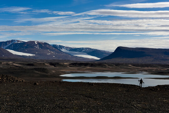 An expedition member, in search of caves for the purpose of climate-change research, takes in the view of Vandredalen.; Greenland.