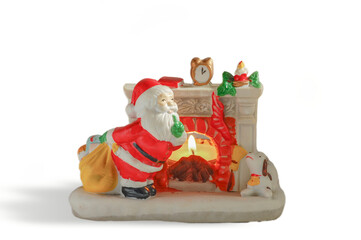 figurine of santa claus next to a fireplace in ceramic, isolated on white background