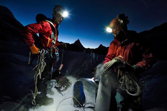 British cave explorers packing the climbing equipment before the cold affects their hands and feet.