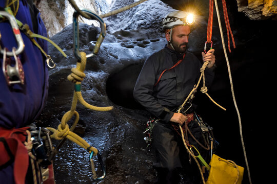 A rigging team descends through the entrance series of El Cenote carrying scanning equipment.