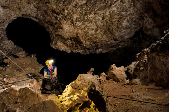 A cave explorer climbing up a rope inside a large vertical drop within Lechuguilla Cave.
