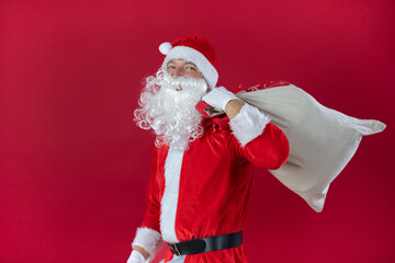 Portrait von einem verkleideten Weihnachtsmann mit Geschenk, isoliert auf roten Hintergrund im Studio im Querformat