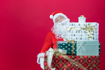 Nahaufnahme von der Hand von einem Weihnachtsmann, der ein Geschenk, vor roten Hintergrund, hält. Weihnachtlicher Hintergrund mit Platzhalter.