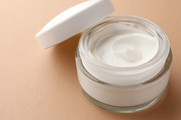 Jar of face cream on beige background, closeup