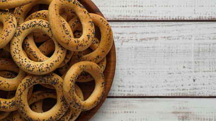 Plate with delicious ring shaped Sushki (dry bagels) on white wooden table, top view. Space for text