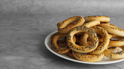 Plate with delicious ring shaped Sushki (dry bagels) on light grey table, closeup. Space for text