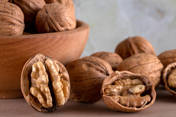 Bowl of walnuts and whole walnut kernels on wooden table
