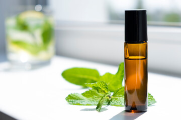 Organic mint essential oil in small bottle and green leaf of peppermint. Extract of herbal...