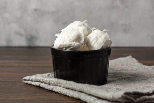 bala de coco or brazilian coconut candy, a gourmet homemade sweet dessert made of coconut on a black bowl.