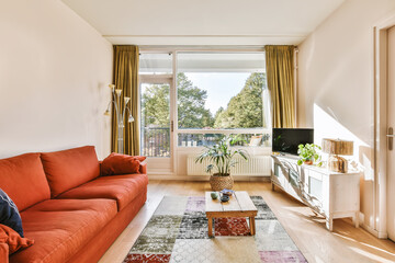 a living room with an orange couch and television set on the floor in front of the window looking...